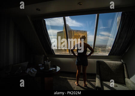 Eine Frau schaut aus einem Hotel Zimmer im Luxor Hotel und Casino in Richtung Mandalay Bay und Delano Resorts in Las Vegas, Nevada, USA. Stockfoto