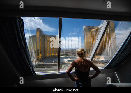 Eine Frau schaut aus einem Hotel Zimmer im Luxor Hotel und Casino in Richtung Mandalay Bay und Delano Resorts in Las Vegas, Nevada, USA. Stockfoto