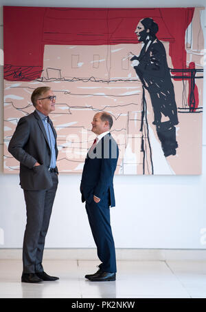 10 September 2018, Berlin: 10.09.2018, Berlin: Dietmar Bartsch (l), Vorsitzender der Parlamentarischen Gruppe der Partei Die Linke, und Olaf Scholz (SPD), Bundesminister der Finanzen, sprechen in einem Korridor in den Deutschen Bundestag vor der Sitzung der SPD-Fraktion im Bundestag. Im Hintergrund hängt ein Gemälde von Susanne Ludwig, die zeigt Marie Juchacz während der ersten Rede einer Frau, die auf die Weimarer Nationalversammlung 1919. Foto: Bernd von Jutrczenka/dpa Stockfoto