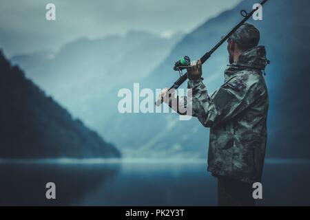 Abend Fliegenfischen Zeit. Kaukasische Fischer mit Angel auf dem Gletschersee Ufer. Stockfoto