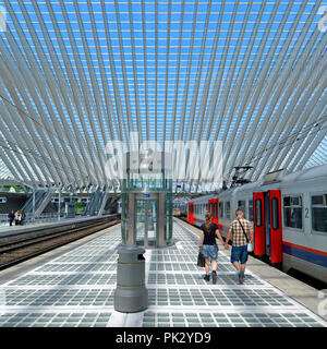 Junges Paar Mann & Frau alleine halten sich an den Händen langen Bahnsteig Lüttich Belgien modernes Gebäude Glas dach Decke blau Himmel Sommer Tag Stockfoto