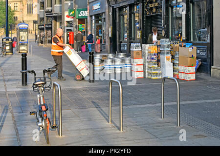 Stadt street scene drayman mit Trolley macht am frühen Morgen Bierfässer und Trinken supply chain Lieferung außerhalb pub Newcastle upon Tyne und England tragen Stockfoto