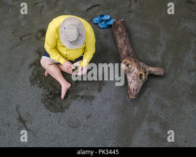 Antenne des Menschen bei seinem Telefon am Strand suchen, Costa Rica Stockfoto