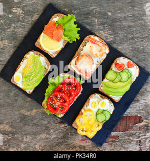 Verschiedene Sandwiches auf die alten hölzernen Hintergrund. Ansicht von oben. Flach. Stockfoto