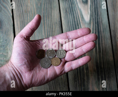 Ein paar Russische metall Rubel liegen in der Hand eines Mannes über einen hölzernen Tab Stockfoto