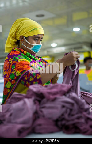 Eine Näherin bei der Arbeit auf einer Maschine innerhalb einer Textilfabrik in Bangladesch. Stockfoto