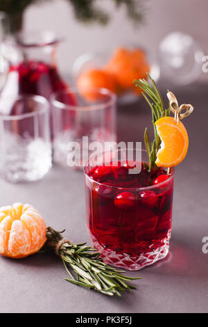 Weihnachten, Thanksgiving Getränke. Herbst, Winter cocktail Grog, heiße Sangria, Glühwein - Rosmarin, Zimt, Cranberry. Auf grau Tabelle. Mit Mandarine, Stockfoto