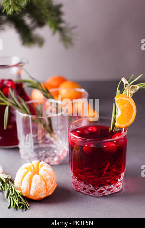 Weihnachten, Thanksgiving Getränke. Herbst, Winter cocktail Grog, heiße Sangria, Glühwein - Rosmarin, Zimt, Cranberry. Auf grau Tabelle. Mit Mandarine, Stockfoto