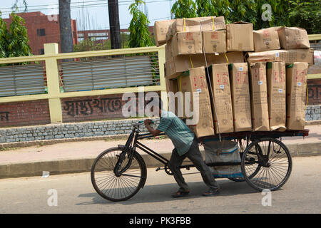 Ein Mann drückte eine Rikscha mit großen Boxen entlang einer Straße in Dhaka, Bangladesch geladen. Stockfoto
