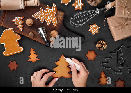 Frau Lebkuchen verzieren Weihnachten Plätzchen mit Puderzucker bestreuen. Weihnachtsvorbereitungen Konzept. Ansicht von oben mit der Kopie. Stockfoto