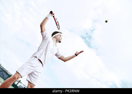 Profi-Tennisspieler tut ein Kick-Tennis auf dem Tennisplatz an einem sonnigen Sommermorgen. Das ist in der Sportswear gekleidet. Stockfoto