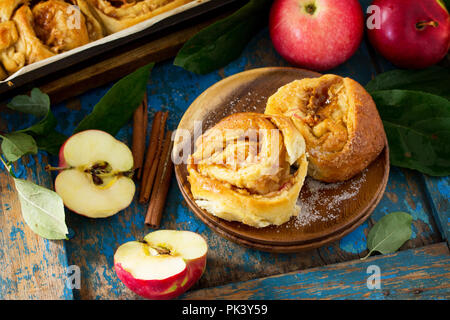 Frische, hausgemachte Brötchen Brötchen mit Äpfeln und Zimt in Glasur auf einem blauen vintage Holz- Hintergrund. Stockfoto