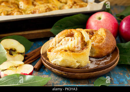 Frische, hausgemachte Brötchen Brötchen mit Äpfeln und Zimt in Glasur auf einem blauen vintage Holz- Hintergrund. Stockfoto