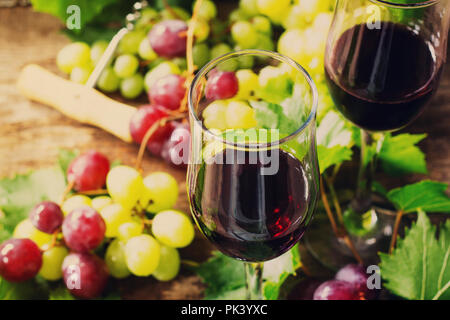 Wein Hintergrund. Rotwein in Gläser, Flaschen, Trauben auf vintage Hintergrund, Wein Konzept. Stockfoto