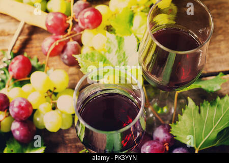 Wein Hintergrund. Rotwein in Gläser, Flaschen, Trauben auf vintage Hintergrund, Wein Konzept. Stockfoto
