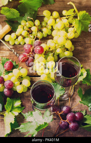 Wein Hintergrund. Rotwein in Gläser, Flaschen, Trauben auf vintage Hintergrund, Wein Konzept. Stockfoto