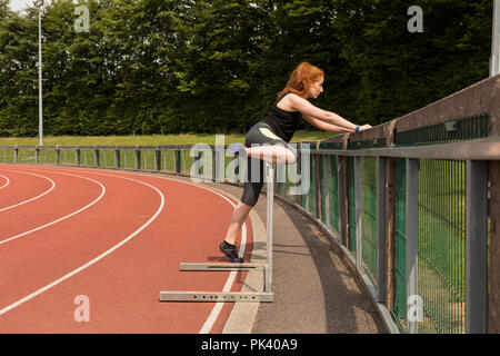Weibliche Athleten trainieren auf Geländer am Sportplatz Stockfoto