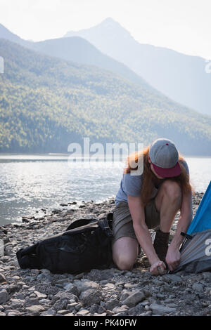 Frau einrichten Zelt in der Nähe des Riverside Stockfoto