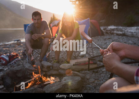 Gruppe von Freunden Heizung hot dog in der Nähe von Lagerfeuer Stockfoto