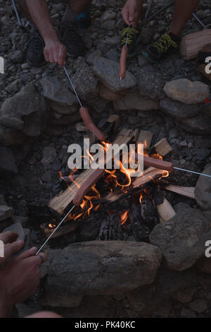 Gruppe von Freunden am Lagerfeuer rösten Hot Dogs. Stockfoto