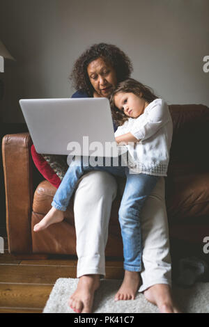 Kleines Mädchen mit Laptop mit Oma auf dem Sofa Stockfoto