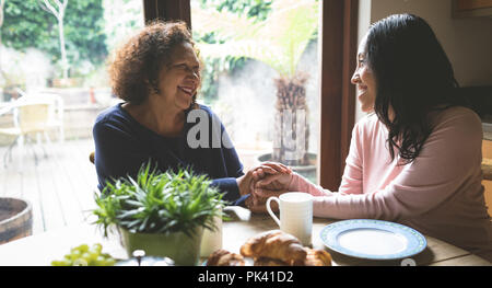 Mutter und Tochter trösten einander auf Esstisch Stockfoto