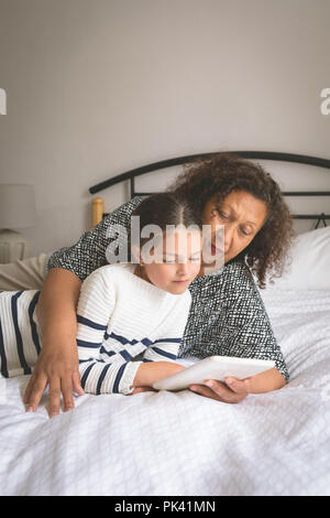 Großmutter und Enkelin mit digitalen Tablet im Schlafzimmer Stockfoto