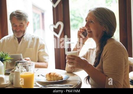 Ältere Frau Gespräch am Handy während Kaffee Stockfoto