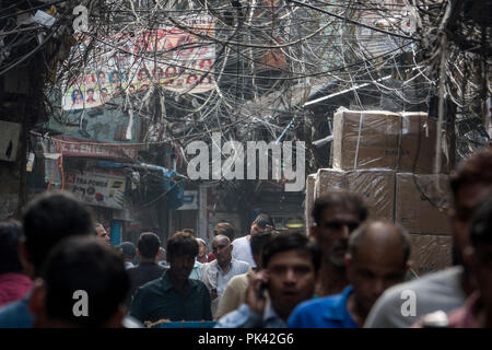 Fußgänger wandern in engen Straße mit großen's tangled Bird's Nest von Stromkabeln Overhead in Old Delhi, Neu-Delhi, Delhi, Indien Stockfoto