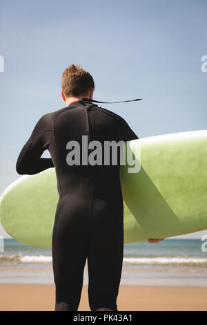 Surfer mit Surfbrett zu Fuß in Richtung Strand