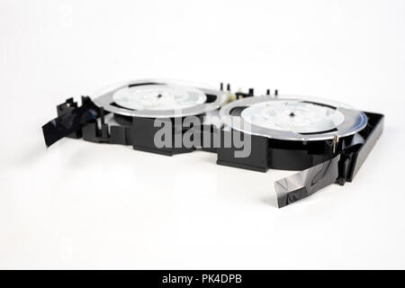 Alte VHS-Kassette mit aufgerollten Band. Beschädigte Datenträger für altes Haus, Bild- und Tonaufzeichnungen. Weißer Hintergrund. Stockfoto