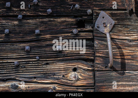 Metall Türgriff auf schäbige schwarze und braune Holztür mit schwarz Nägel Stockfoto