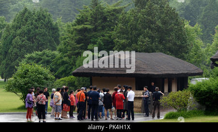 Touristen, die sich in der regen am Eingang zum Museum von Kim Il Sung Geburtshaus Mangyongdae Forest Park, Pyongyang, Nordkorea Stockfoto