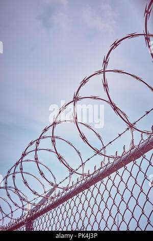 Farbe getonte Bild von einem rasiermesser Stacheldrahtzaun gegen den Himmel, Inhaftierung Konzept, selektive konzentrieren. Stockfoto