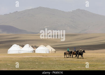 Song Kul, Kirgistan, 8. August 2018: Drei Kirgisen ihre Pferde Reiten durch die Steppe bei Song Kul See in Kirgisistan Stockfoto