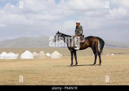 Song Kul, Kirgistan, 8. August 2018: einem Kirgisischen sitzt auf einem Pferd bei Song Kul See in Kirgisistan Stockfoto