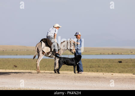 Song Kul, Kirgistan, 8. August 2018: Zwei Jungen und einem Esel bei Song Kul See in Kirgisistan Stockfoto