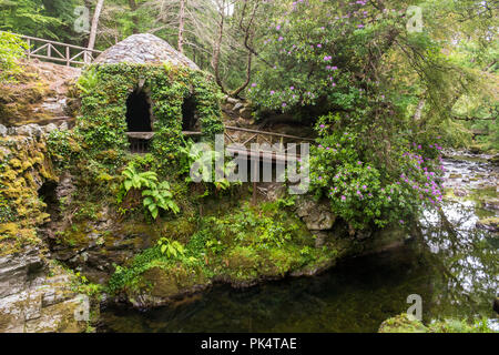 Der Eremitage und dem Fluss, der Eremitage in Tollymore Forest Park, ist ein hübscher Stein Schutz in Efeu bedeckt am Riverwalk neben dem Shimna River, Stockfoto