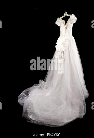 Blick auf die Rückseite der wunderschöne Hochzeit Kleid hängen und isoliert auf schwarzen Hintergrund. Großen Bogen auf der Rückseite. Stockfoto