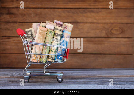 Warenkorb mit Geld aus verschiedenen Ländern: Dollar, Euro, Griwna, Rubel auf alten Holz Hintergrund. Stockfoto