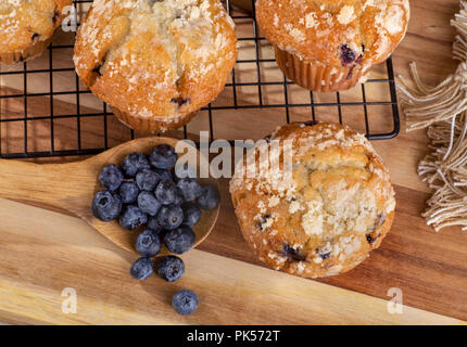 Ansicht von oben von einem Esslöffel Blaubeeren und blueberry muffins auf Holz- Oberfläche Stockfoto