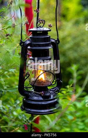 Hängende Metall und Glas altmodische Gartenlaterne mit einer Flamme im Inneren brennen Stockfoto