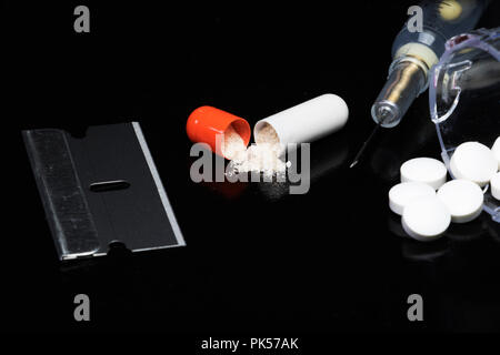 Droge-utensilienien auf schwarzem Hintergrund. Pillen, Nadeln, Rasierklingen. Narkotische Objekte Drogenmissbrauch und Drogenabhängigkeit. Überdosierung. Stockfoto