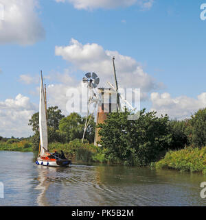 Eine Yacht segeln von Turf Fen Entwässerung Mühle am Fluss Ameise auf den Norfolk Broads gegenüber wie Hügel, Ludham, Norfolk, England, Vereinigtes Königreich, Europa. Stockfoto