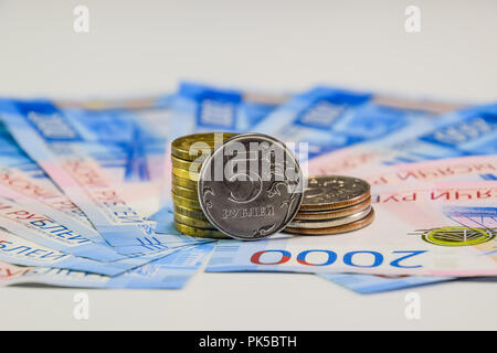 Russische Banknoten und Münzen. Eine Handvoll Münzen auf Neue Russische Banknoten im Wert von 2000 und 200 Rubel. Stockfoto