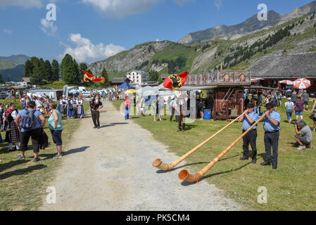 Engstlenalp, Schweiz - 4 August 2018: die Leute spielen Das alphorn und Fahnenträger auf Engstlenalp in den Schweizer Alpen Stockfoto