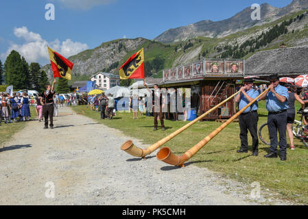 Engstlenalp, Schweiz - 4 August 2018: die Leute spielen Das alphorn und Fahnenträger auf Engstlenalp in den Schweizer Alpen Stockfoto