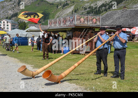 Engstlenalp, Schweiz - 4 August 2018: die Leute spielen Das alphorn und Fahnenträger auf Engstlenalp in den Schweizer Alpen Stockfoto