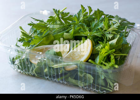 Frische Petersilie und Rucola/Rucola Blätter mit Zitrone in Kunststoffbehälter auf. Ökologische Lebensmittel. Stockfoto