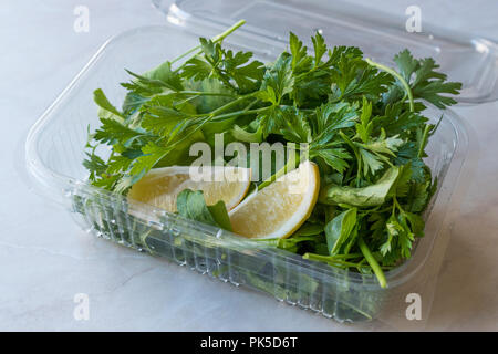 Frische Petersilie und Rucola/Rucola Blätter mit Zitrone in Kunststoffbehälter auf. Ökologische Lebensmittel. Stockfoto
